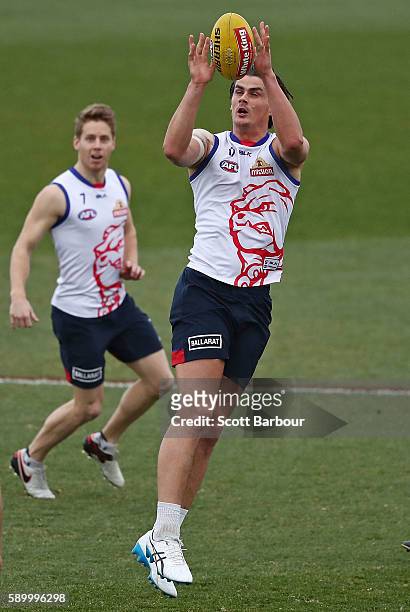 Tom Boyd of the Bulldogs marks the ball as Lachie Hunter of the Bulldogs looks on during a Western Bulldogs AFL training session at Whitten Oval on...