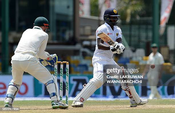 Sri Lanka's captain Angelo Mathews plays a shot as Australia's wicketkeeper Peter Nevill looks on during the fourth day of the third and final Test...