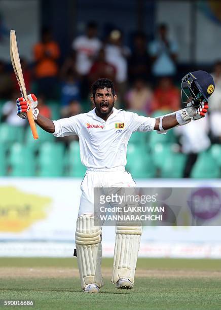 Sri Lanka's Kaushal Silva raises his bat and helmet in celebration after scoring a century during the fourth day of the third and final Test cricket...