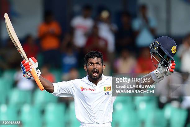 Sri Lanka's Kaushal Silva raises his bat and helmet in celebration after scoring a century during the fourth day of the third and final Test cricket...