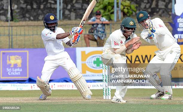 Sri Lanka's Kaushal Silva plays a shot as Australia's wicketkeeper Peter Nevill and fielder David Warner react during the fourth day of the third and...