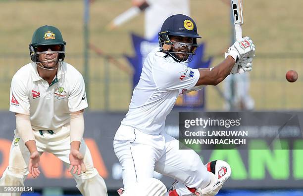 Sri Lanka's Dinesh Chandimal plays a shot as Australia's David Warner looks on during the fourth day of the third and final Test cricket match...