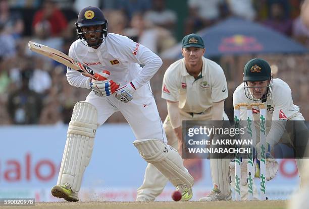 Sri Lanka's Dhananjaya de Silva plays a shot as Australia's wicketkeeper Peter Nevill and David Warner look on during the fourth day of the third and...