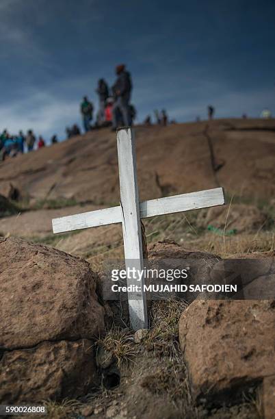 Miners stand next to white cross marking the spot where a miner was gunned down during commemorations for the fourth anniversary of the Marikana...