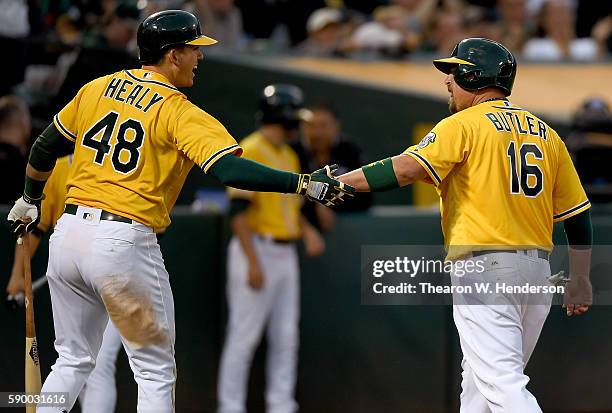 Billy Butler of the Oakland Athletics is congratulated by Ryon Healy after Butler scored against the Seattle Mariners in the bottom of the six inning...