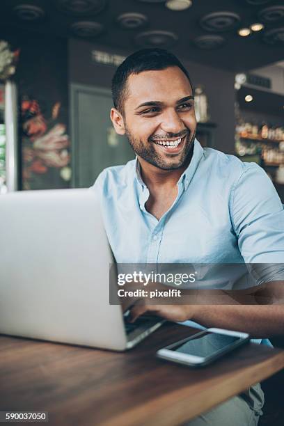 young man with laptop in cafe - good looking indian men stock pictures, royalty-free photos & images