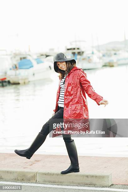 pretty happy woman wearing rain coat at the port - oil skin stock pictures, royalty-free photos & images