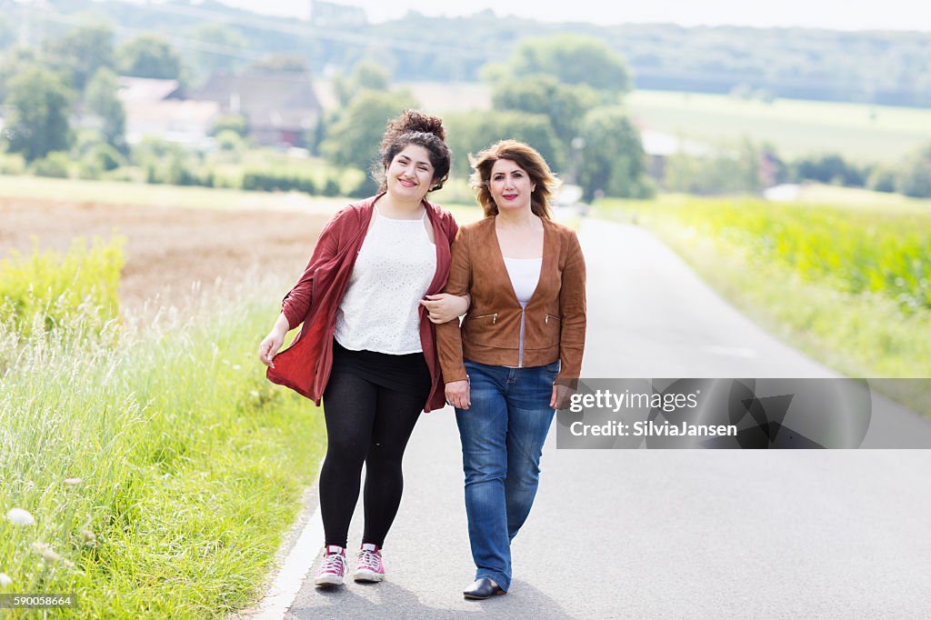 Mature mother and adult daughter walking together