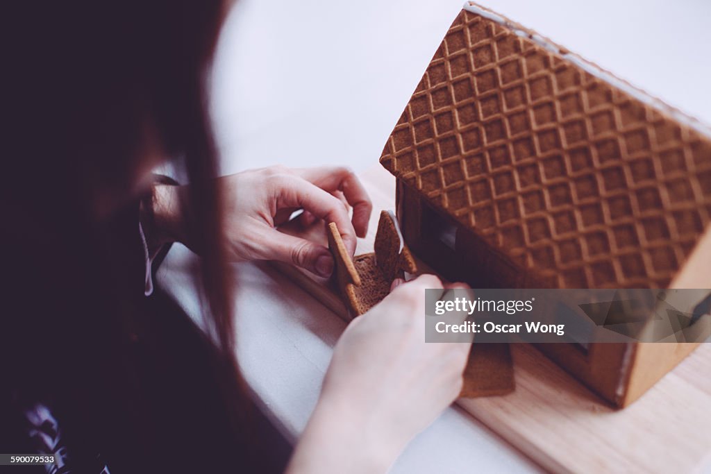 A young lady is making a gingerbread house