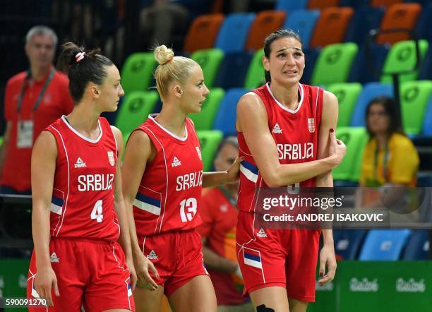 Serbia's forward Sonja Petrovic holds her arm, escorted by Serbia's point guard Tamara Radocaj and Serbia's point guard Milica Dabovic, after falling...