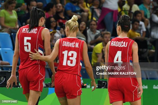 Serbia's point guard Tamara Radocaj and Serbia's point guard Milica Dabovic escort Serbia's forward Sonja Petrovic after she fell and injured her...