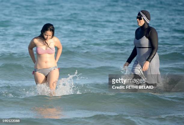 Tunisian women, one wearing a "burkini", a full-body swimsuit designed for Muslim women, swim on August 16, 2016 at Ghar El Melh beach near Bizerte,...