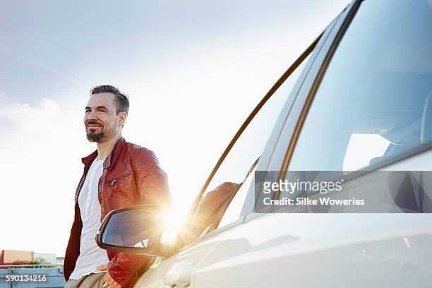 middle-aged man standing beside his car - autofoto stockfoto's en -beelden