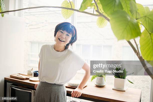mature woman standing at kitchen - 50 year old japanese woman stock pictures, royalty-free photos & images
