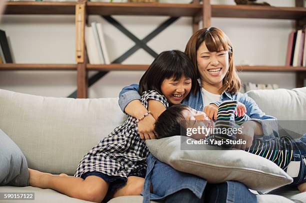 mother embracing son and daughter on sofa. - wealthy family inside home stock pictures, royalty-free photos & images