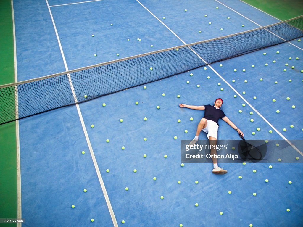 Male tennis player lying on ground