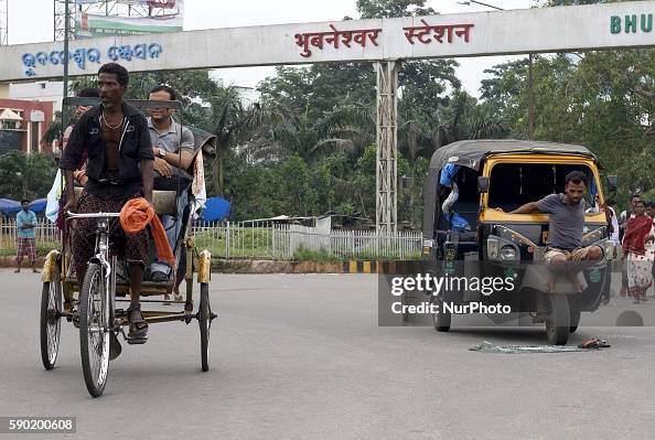 An auto rickshaw driver sits in front of his vehicle as it broken by ...
