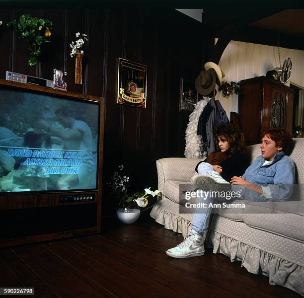 Child actors Alyssa Milano with Scott Grimes, interacting, watching their film "Commando" at her home in LA, 1/28/1986. .