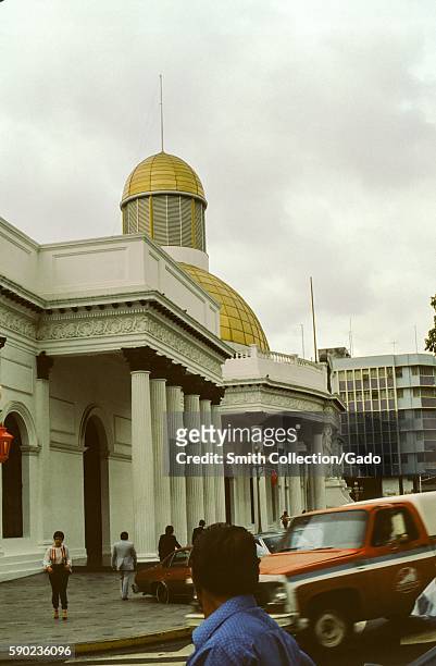 People walk past the facade and gold dome of the National Assembly building in Caracas, Venezuela, 1970. .