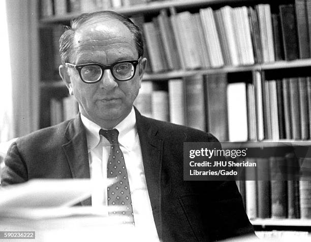 Portrait of American historian and biographer David Herbert Donald sitting in front of bookshelves, 1962. .