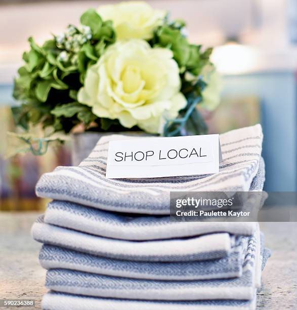 shop local sign on stack of pretty tea towels - gift shop ストックフォトと画像