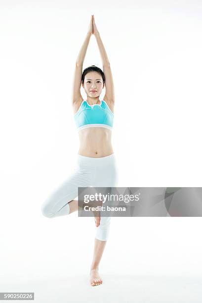 young asian woman standing in yoga tree posture - trainer cutout stockfoto's en -beelden
