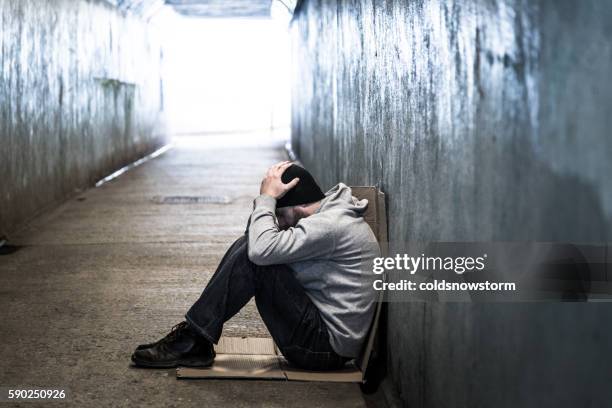 homeless adult male sitting in subway tunnel, hands on head - homeless winter stock pictures, royalty-free photos & images
