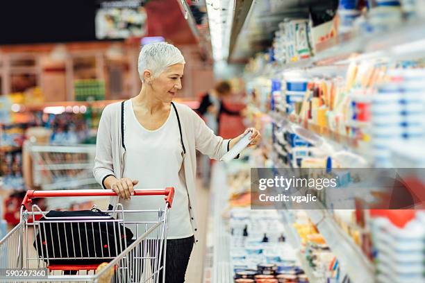 mature woman groceries shopping. - voedingslabel stockfoto's en -beelden