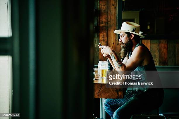 man looking at smartphone in restaurant - solo un uomo di età media foto e immagini stock
