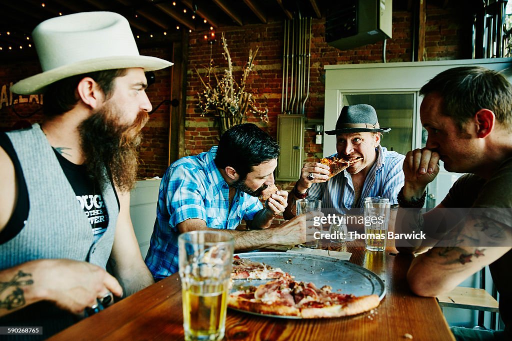 Group of friends sharing pizza and beers