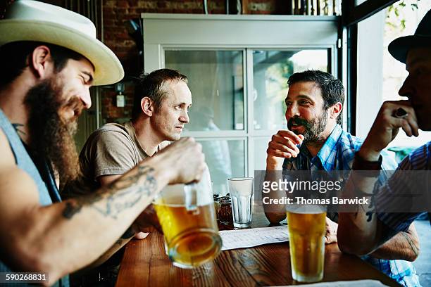 group of friends sharing drinks in restaurant - mature men group stock pictures, royalty-free photos & images