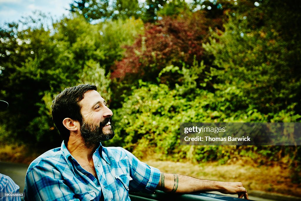 Smiling man riding in convertible with friends