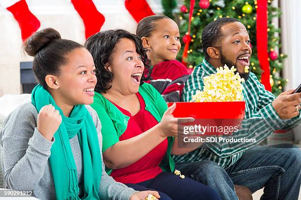 enthusiastic sports fan watch football game on tv during christmastime - mid winter ball imagens e fotografias de stock