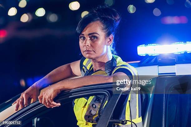 female police officer standing next to patrol car - verkeerspolitie stockfoto's en -beelden