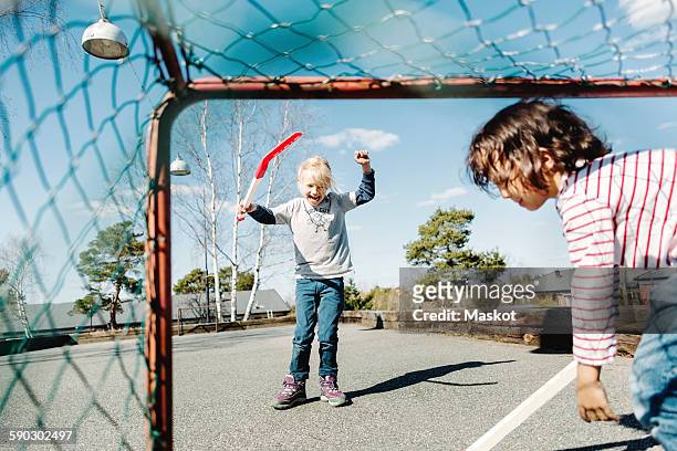 excited girl gesturing while playing hockey with boy at yard - female hockey player stock pictures, royalty-free photos & images