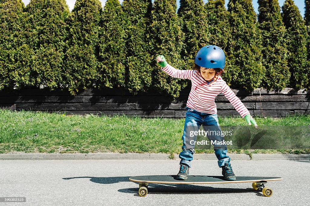 Full length of boy balancing on skateboard at yard