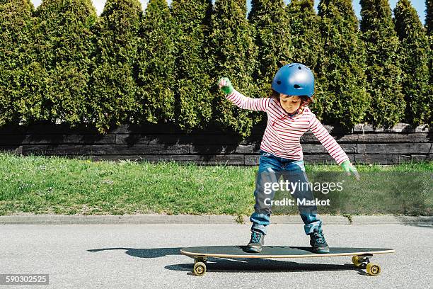 full length of boy balancing on skateboard at yard - children playing in yard stock-fotos und bilder