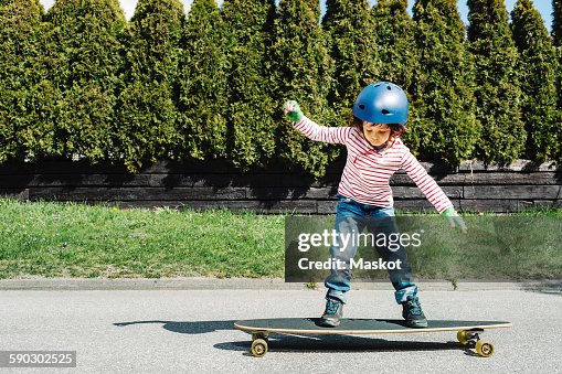 Full length of boy balancing on skateboard at yard Full length of boy balancing on skateboard at yard