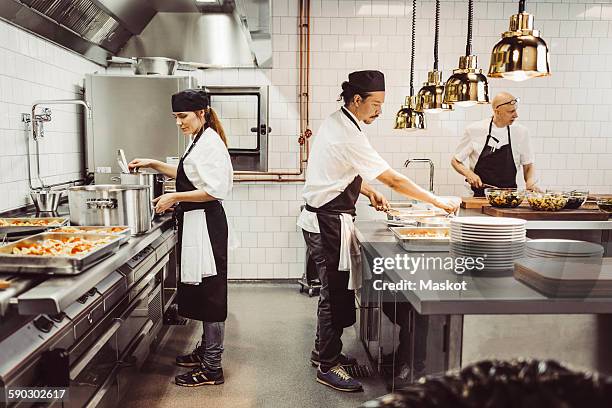 male and female chefs preparing food in commercial kitchen - chef full length stock pictures, royalty-free photos & images