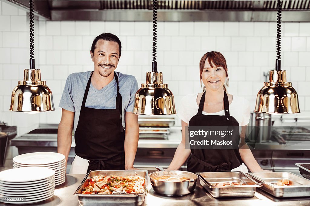Portrait of happy chefs standing in commercial kitchen counter