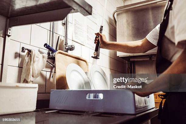 midsection of male chef washing plates in crate at kitchen - wash the dishes stockfoto's en -beelden