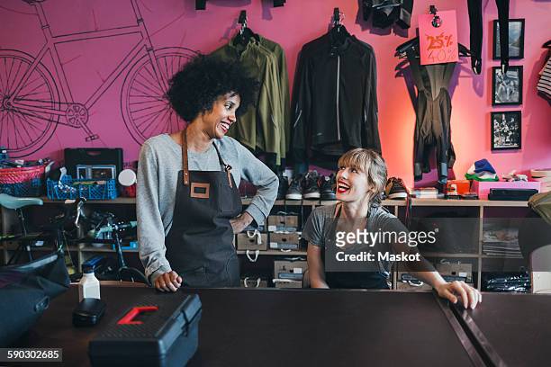 happy female mechanics looking at each other at table - sportgeschäft stock-fotos und bilder