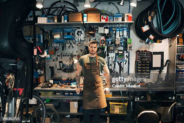 portrait of confident mechanic leaning on workbench - workshop tools stock pictures, royalty-free photos & images