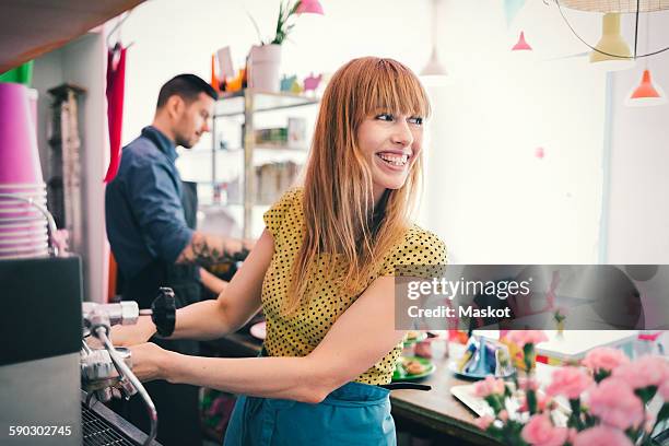 happy female barista looking away while using coffee maker in caf_ - barista stock pictures, royalty-free photos & images