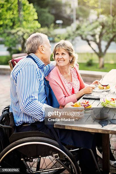 happy mature couple looking at each other while having food in yard - formal garden fotografías e imágenes de stock