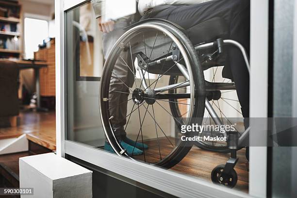 low section of son and father in wheelchair lift at home - accessibilité aux personnes handicapées photos et images de collection