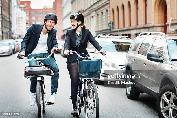 happy business people riding bicycles on city street - man and woman and car stock pictures, royalty-free photos & images