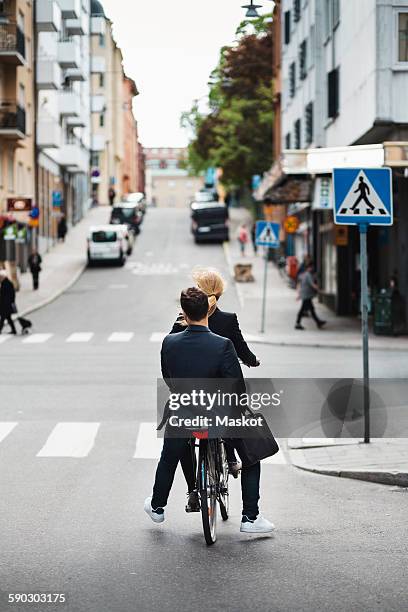 rear view of business people riding bicycle on city street - couple crossing street stock pictures, royalty-free photos & images