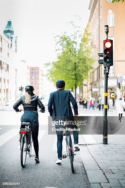 rear view of business people with bicycles waiting at zebra crossing on city street - road signal 個照片及圖片檔