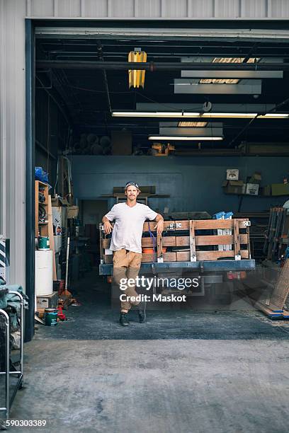 portrait of carpenter leaning on pick-up truck at workshop - lean manufacturing stockfoto's en -beelden